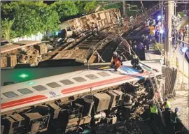  ?? Ritchie B. Tongo EPA/Shuttersto­ck ?? RESCUERS search the Puyuma Express, which had 366 passengers when it went off the tracks on a wide curve. Officials have not released a cause for the incident.