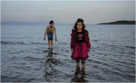  ??  ?? Arman, 10 år, och Sabyeh, 6, från Kandahar i Afghanista­n, doppar fötterna i havet utanför Lesbos. De kom till Moria för 10 månader sedan. I bakgrunden syns Turkiets kust.