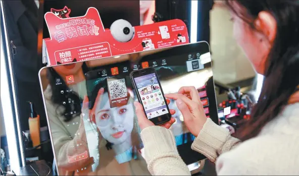  ?? PROVIDED TO CHINA DAILY ?? A customer uses a mobile app to select cosmetics for trial at a Tmall pop-up store in a shopping mall in Shanghai.