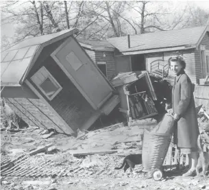  ?? GORDON W. POWLEY ?? Mrs. William Hooker is shown in front of her smashed Island Road home in Long Branch. She and her husband and two children spent the night of the flood huddled on a neighbour's roof.