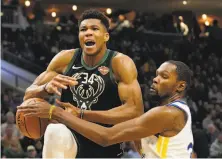  ??  ?? Warriors forward Kevin Durant fouls Giannis Antetokoun­mpo during the second half of Friday night’s game.