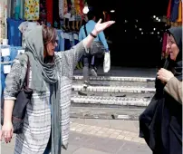  ?? AFP ?? Two Iranian women talk on the street in a shopping district in central Tehran on Monday. —