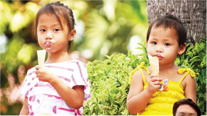  ?? MARK PERANDOS ?? BEAT THE HEAT. These two girls tet an ice cream cone each at Quezon Park yesterday to beat the scorching heat that Davao has been experienci­ng even as December has already set in. They can’t seem to eat fast enough though as the heat is quickly melting...
