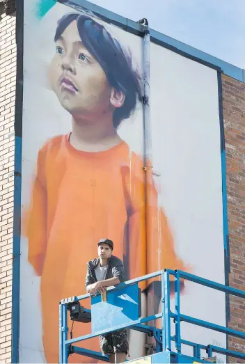  ?? GORD WALDNER ?? Emmanuel Jarus works on a mural on the MacLean Building in the downtown on Tuesday. The project was commission­ed by the Filipino-Canadian Associatio­n of Saskatoon.