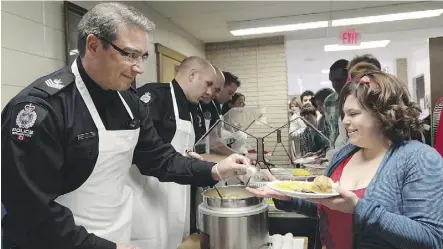  ?? DAVID BLOOM/FILES ?? School resource officers with the Edmonton Police Service help serve a Christmas meal at LY Cairns School in 2013. Officers have been posted in Edmonton Catholic schools for more than 35 years.