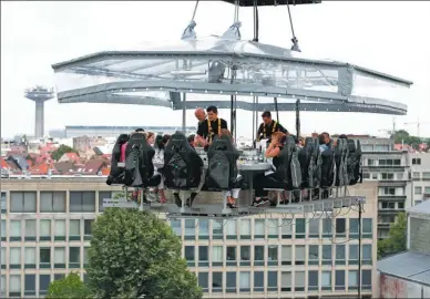  ?? XINHUA ?? Customers dine at an “air restaurant” 40 meters off the ground in Brussels, Belgium, on Saturday. The dinner-in-the-sky concept originated in Belgium and has spread to dozens of countries. The Brussels “air restaurant” can accommodat­e 22 diners, with...