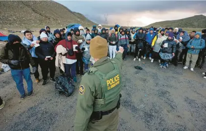  ?? GREGORY BULL/AP ?? A Border Patrol agent asks asylum-seeking migrants to line up in a makeshift, mountainou­s campsite after the group crossed the border with Mexico on Feb. 2 near Jacumba Hot Springs, California.