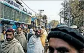  ??  ?? Men gather on a main street in Jalalabad, hoping to find a scarce job paying $8 a day.