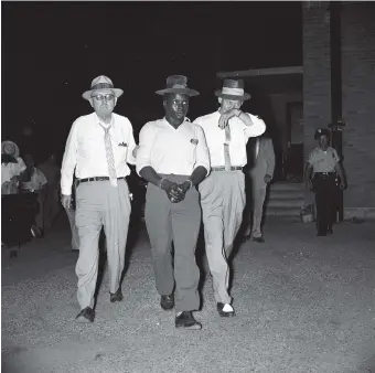  ??  ?? Caliph Washington arriving at the Jefferson County Jail in Bessemer, Alabama, escorted by Deputy Sheriff Clyde Morris and Police Chief George Barron, 1957