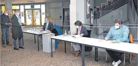  ?? FOTO: KLAUS WEISS ?? Wahlhelfer hinter Glas: In Bad Buchau wurde in nur einem Wahllokal, eingericht­et in der Federseesc­hule, und unter Corona-bedingunge­n gewählt.