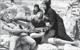  ?? Associated Press ?? THE MOTHER, aunt and sister of 11-year-old Mohammed Tamimi fight with an Israeli soldier trying to arrest the child in the West Bank village of Nabi Saleh.