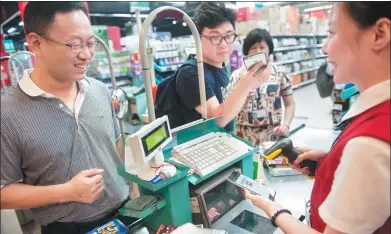  ?? PROVIDED TO CHINA DAILY ?? A cashier scans a buyer's WeChat Pay code on his mobile phone at a supermarke­t in Shenzhen, Guangdong province.