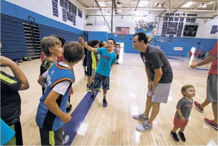  ?? JANE PHILLIPS/FOR THE NEW MEXICAN ?? UNM men’s basketball head coach Paul Weir talks Saturday with campers during the Lobos’ youth skills camp at St. Michael’s High School. 130 kids from first grade through eighth grade attended the camp. Weir’s 2-year-old son, Theodore, is at right.