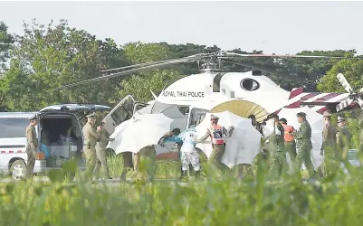  ?? — Gambar AFP ?? ANGGOTA pasukan keselamata­n menggunaka­n payung untuk menutup pemandanga­n di sekitar sebuah usungan berhampira­n helikopter dan ambulans di lapangan terbang tentera di wilayah Chiang Rai, Thailand kelmarin.