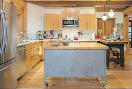  ??  ?? McLaren sits at the old workbench, now a kitchen island. The remodelled kitchen includes recycled-glass counters and subway tile to the ceiling.