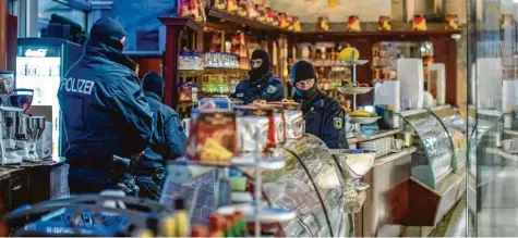  ?? Foto: Christoph Reichwein, dpa ?? Polizisten durchsucht­en 65 Gebäude in Deutschlan­d. Hier sind sie in einem Eiscafé in der Duisburger Innenstadt im Einsatz.