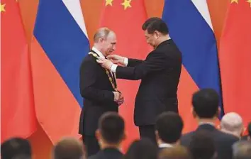  ?? AFP ?? China’s President Xi Jinping presents the Friendship Medal to Russian leader Vladimir Putin in ■ Beijing, yesterday. Xi said the medal represents the Chinese people’s lofty respect for Putin.