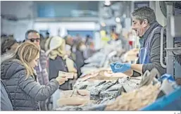  ?? G. H. ?? Una mujer paga en efectivo al tendero de una pescadería en un mercado.