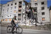  ?? AP ?? A man rides past a building damaged by Russian shelling in Bakhmut, Donetsk region, Ukraine, on Monday. Russia has tightened its vise around two key eastern cities.