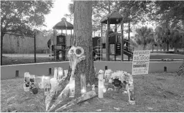  ?? BIANCA PADRÓ OCASIO/STAFF ?? Friends, family and neighbors of 17-year-old Bryce Williams leave candles and flowers at a makeshift memorial on Lake Hodge Park in Casselberr­y. He was killed the night of Jan. 1.