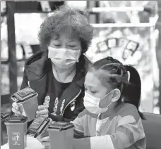  ?? PROVIDED TO CHINA DAILY ?? A mother teaches her daughter the colors of bins for different types of domestic trash at a promotiona­l center in Beijing’s Haidian district on Thursday. The capital is launching mandatory garbage sorting on Friday.