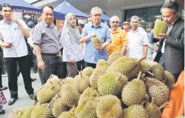  ??  ?? Badruddin (centre) looking at the durians on sale during the MyBest Buy programme. — Bernama photo