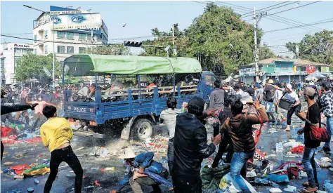  ?? [ Reuters ] ?? Demonstran­ten bewerfen in Mandalay Polizisten mit Steinen und fordern die Freilassun­g von Aung San Suu Kyi.