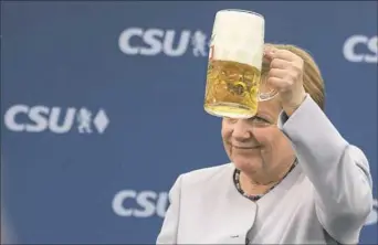  ?? Matthias Balk/dpa via AP ?? German Chancellor Angela Merkel lifts a glass of beer Sunday during an election campaign of her Christian Democratic Union and the Christian Social Union in Munich.