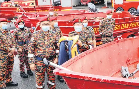  ?? — Photo by Chimon Upon ?? Khirudin (holding life jacket) and Bomba officers and personnel show some of the rescue boats on standby in the event of floods.