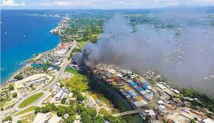  ?? ROBERT TAUPONGI AFP VIA GETTY IMAGES ?? Smoke from burning buildings rise from Honiara on the Solomon Islands on Thursday, the second day of rioting that left the capital ablaze and threatened to topple the Pacific nation’s government. Australia agreed to commit troops to restore order.