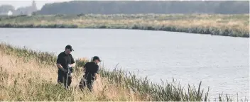  ?? Picture: PA ?? Two police officers on the bank of the River Welland, investigat­ing the disappeara­nce of 17-year-old Bernadette Walker, searching a site in Cowbit.