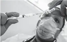  ?? Mary Altaffer / Associated Press file ?? Dr. Yomaris Pena extracts the last bit of vaccine from a vial so as not to waste it earlier this year at a vaccinatio­n site in New York.