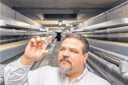  ?? RANDY MONTOYA/ SANDIA LABS ?? Joshua Whiting, an analytical chemist at Sandia National Laboratori­es, examines a gas sensor that could be used in a sensitive portable system to detect chemical weapons or airborne toxins.