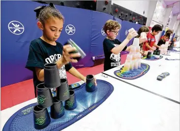  ?? PHOTOS BY CURTIS COMPTON / CCOMPTON@AJC.COM ?? The Norcross Stackers (from left) Leah Hairston, Jonathan Driggers, Ellie Grogin, Matthew Follmer, Sophia Hairston and Nicholas Follmer practice their unusual sport at Peachtree Elementary School last month in Peachtree Corners.