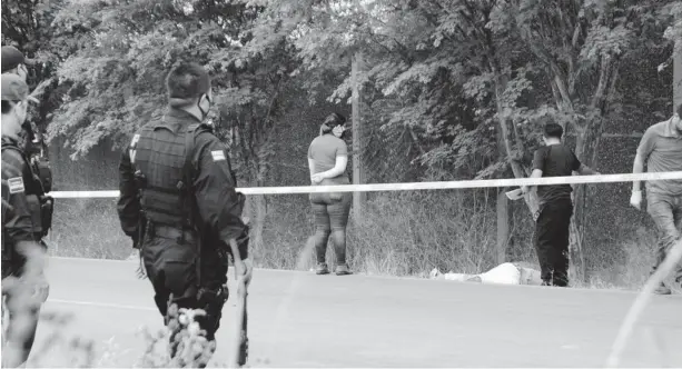  ?? FOTO: MARCO MILLÁN ?? > Policías observan a poca distancia mientras peritos estudian la escena del crimen.