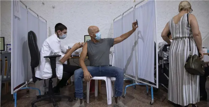  ?? Ap ?? SMILE: An Israeli man takes a selfie while receiving his booster shot at a vaccinatio­n center last week in Ramat Gan, Israel. Israeli Foreign Affairs Ministry spokesman Lior Haiat, below, says booster shots are proving effective against the delta variant.