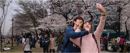  ??  ?? Smart phone: A couple take a selfie beneath cherry blossoms on Yeouido island in Seoul. The smartphone is today the ‘one device to rule them all’. — AFP