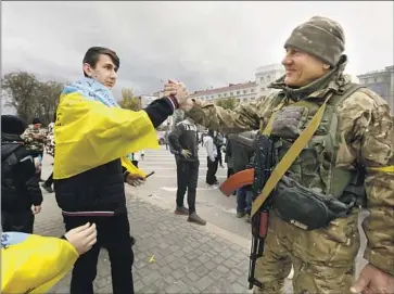  ?? CAROLYN COLE Los Angeles Times ?? A UKRAINIAN soldier is greeted in Kherson, recently liberated after months of Russian occupation. Russian President Vladimir Putin has not commented publicly on the pullout, a humiliatin­g defeat for his forces.