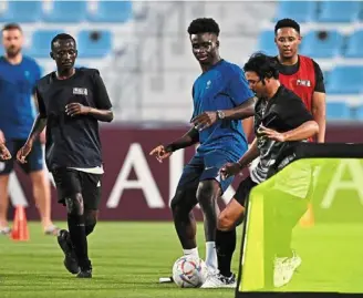  ?? — AFP ?? Game on: england’s bukayo Saka (thrid from right) plays football with migrant workers at the al Wakrah Stadium in doha.