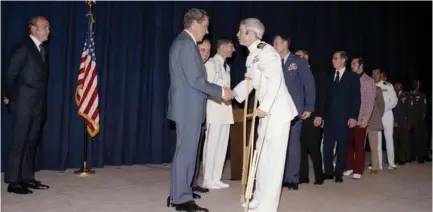  ?? (National Archives/Reuters) ?? US PRESIDENT Richard Nixon greets former Vietnam prisoner of war John McCain at a pre-POW dinner reception in Washington in 1973.