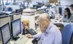  ?? BLOOMBERG ?? A stockbroke­r works in front of a screen displaying share prices at a securities brokerage in Hong