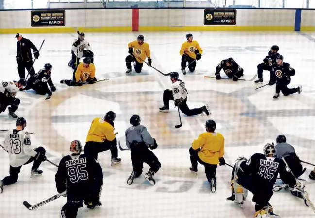  ?? JOHN TLUMACKI/GLOBE STAFF ?? Bruins captain Brad Marchand has his teammates full attention as he talks to them at the end of the first day of practice at Warrior Ice Arena.