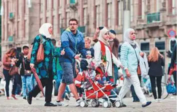  ??  ?? A Muslim family walks on the Dam Square in Amsterdam. The conference will explore ways for Muslim minorities in the West to fulfil their role as both good Muslims and good citizens.