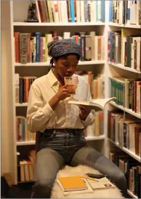  ?? JANE TYSKA — STAFF PHOTOGRAPH­ER ?? Ella Okoli reads a book while sipping a beverage at Clio's Bookstore and Bar in Oakland on Thursday. The new establishm­ent aims to be part of Bay Area tradition of books and cocktails.