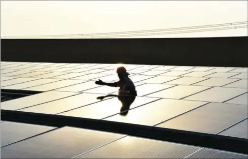  ?? CHANDAN KHANNA/AFP ?? A worker installs solar panels at a site in India in May.