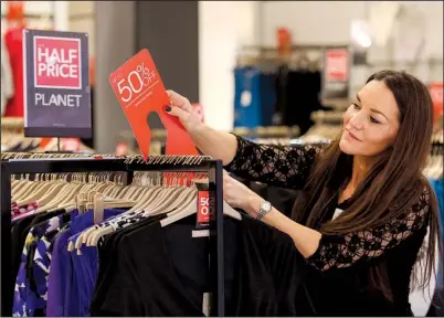  ?? Bloomberg News/CHRIS RATCLIFFE ?? An employee attaches a sign advertisin­g a discount of up to 50 percent inside a Debenhams store on Black Friday in London.