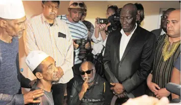  ?? TRACEY ADAMS African News Agency (ANA) ?? POLICE Minister Bheki Cele consoles Mogamat Alwie Noordien (sitting second from left), father of Ameerodien in Hanover Park yesterday. |