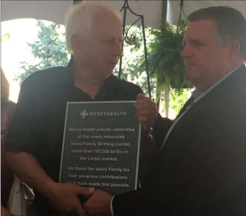  ?? KEVIN MARTIN — THE MORNING JOURNAL ?? Jon Veard, left, is presented with a plaque from Ed Oley, right, on July 31 in recognitio­n of his generous contributi­on to Mercy Health-Lorain Hospital which culminated in the Veard Family Birthing Center.