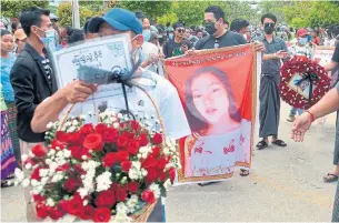  ?? STR AFP VIA GETTY IMAGES ?? Mourners carry images of Mya Thwet Thwet Khine during a funeral service for her Sunday in Naypyitaw, Myanmar. She died after being shot Friday during a rally protesting the military coup.