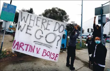  ?? PHOTOS BY SHMUEL THALER — SANTA CRUZ SENTINEL ?? People living in an encampment in and around a Front Street parking lot and their supporters raise a banner as city workers and a group of police officers gather across the street. The city had ordered evacuation of the site, but after arriving on the scene at 8 a.m. Wednesday morning, city workers and police left two hours later without taking any action.